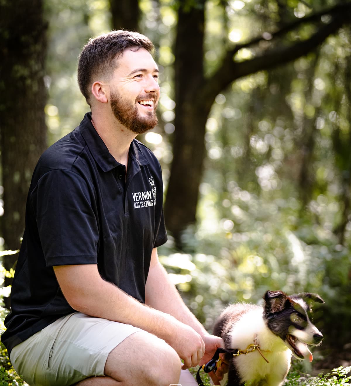Ben Vernon kneeling in the woods with a puppy during a training session